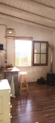 a kitchen with a table and a stool in a room at La calendula eco cabaña in Los Hornillos