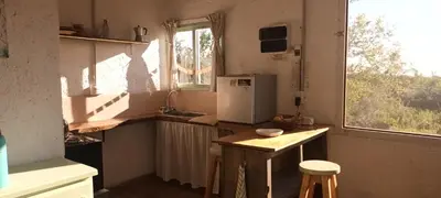 a small kitchen with a refrigerator and a window at La calendula eco cabaña in Los Hornillos