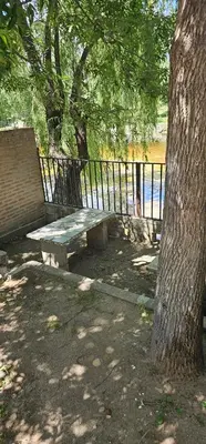 a picnic table under a tree next to a fence at Departamentos Las Termas de Brochero in Villa Cura Brochero