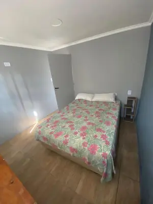 a small bedroom with a bed with a floral blanket at Lo de joel in Villa Carlos Paz