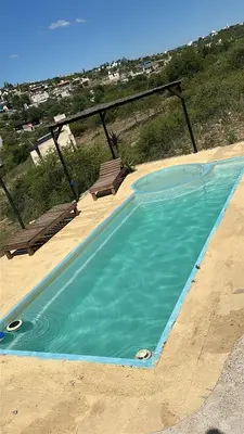 a blue swimming pool with a bench and the ocean at Lo de joel in Villa Carlos Paz