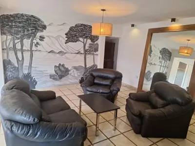 a living room with two leather chairs and a mural at Casa Rumipal in Villa Rumipal