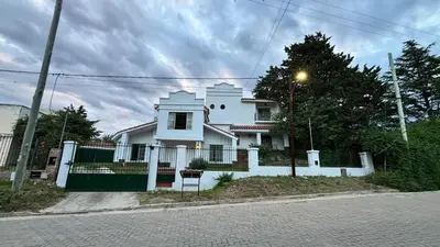 a white house with a fence in front of it at Gran Casa en Villa Del Lago in Villa Carlos Paz