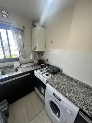 a small kitchen with a stove and a sink at Dpto con piscina , asador & terraza in Villa Carlos Paz