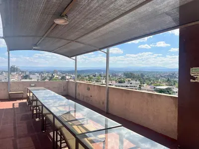 a balcony with tables and chairs on a building at Dpto con piscina , asador & terraza in Villa Carlos Paz