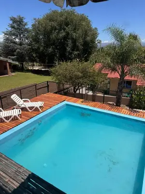 a large swimming pool with a deck and two lawn chairs at Las Casitas de Euge in Villa Carlos Paz