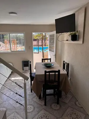 a dining room with a table and a tv on the wall at Las Casitas de Euge in Villa Carlos Paz