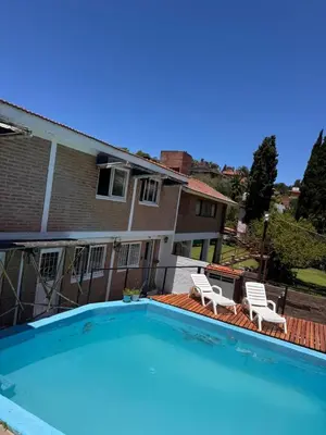 a swimming pool with two chairs and a house at Las Casitas de Euge in Villa Carlos Paz