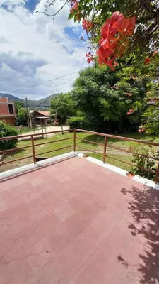 a patio with a fence and a tree with red flowers at Gran Malvina in Villa Carlos Paz