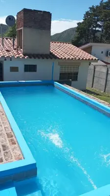 a large blue swimming pool in front of a house at Gran Malvina in Villa Carlos Paz