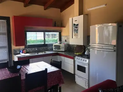 a kitchen with a white refrigerator and a table with a microwave at Departamento Los Gigantes in Villa Carlos Paz