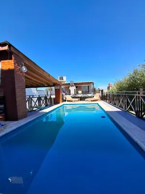 a blue swimming pool with a house in the background at Complejo Cuarto Menguante in Arroyo de Los Patos