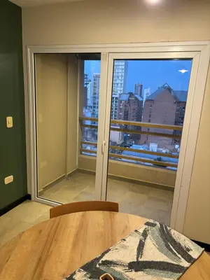 a room with a table and a view of a city at Departamento amoblado 1 dormitorio Río 4 in Río Cuarto