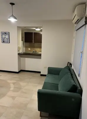 a living room with a green couch and a kitchen at Departamento amoblado 1 dormitorio Río 4 in Río Cuarto