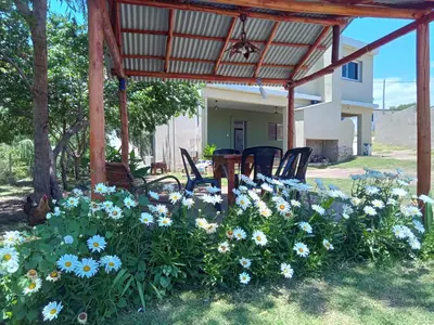 a garden with blue flowers and chairs under a pergola at Casa florez in Mina Clavero