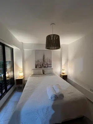 a bedroom with a large white bed with two lamps at illia home in Cordoba