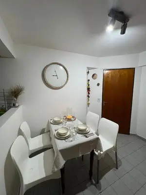 a dining room table with white chairs and a clock on the wall at illia home in Cordoba