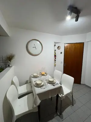 a dining room table with white chairs and a clock on the wall at illia home in Cordoba