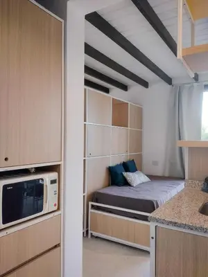 a small bedroom with a bed and a microwave at Refugio Verde en Nono, Córdoba in Nono
