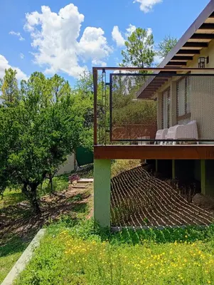 a deck with chairs on the side of a house at Refugio Verde en Nono, Córdoba in Nono