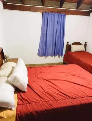 a bedroom with two beds with red sheets and a window at Vistas valle in Santa Rosa de Calamuchita