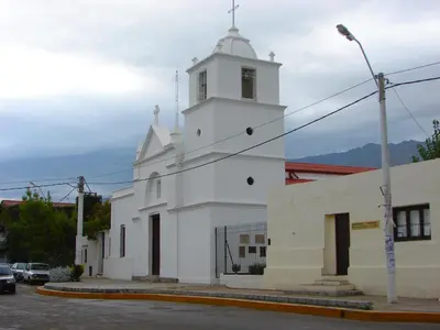 a white church with a steeple on a street at Alojamiento Quilo in Merlo