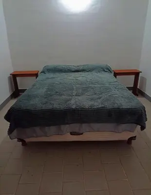 a bed with a green blanket on top of it at Alojamiento Quilo in Merlo