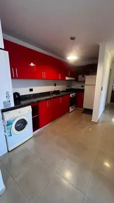 a kitchen with red cabinets and a washing machine at Dto con pileta en Carlos Paz 28! in La Cuesta