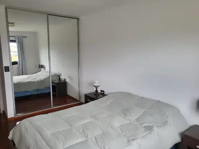 a bedroom with a white bed and a large mirror at Dto con pileta en Carlos Paz 28! in La Cuesta