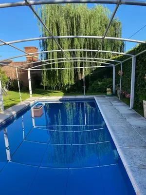 a blue swimming pool with a pergola at Chalet Espectacular in Villa Carlos Paz