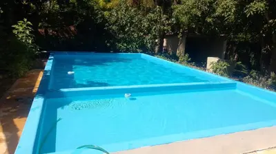 a blue swimming pool with trees in the background at Los Nogales in Los Hornillos