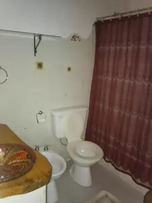 a bathroom with a toilet and a red shower curtain at Los Nogales in Los Hornillos