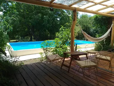 a deck with a hammock and chairs and a pool at Los Nogales in Los Hornillos