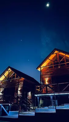 two wooden buildings with the moon in the sky at Vista Encantada Complejo in Villa Carlos Paz