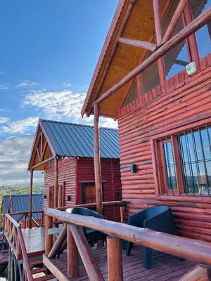 a log cabin with a porch and chairs on a deck at Vista Encantada Complejo in Villa Carlos Paz