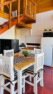 a kitchen with a wooden table and white chairs at Vista Encantada Complejo in Villa Carlos Paz
