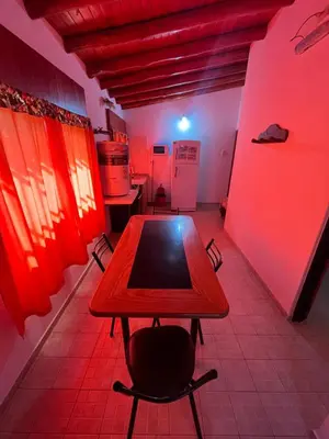 a room with a table and a kitchen with red lights at Departamento en Complejo Panaholma in Villa Cura Brochero