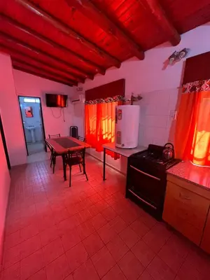 a kitchen with a table and a kitchen with orange curtains at Departamento en Complejo Panaholma in Villa Cura Brochero