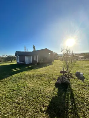 a house in a field with a bench in the yard at Cabaña Aguaribay in Mina Clavero