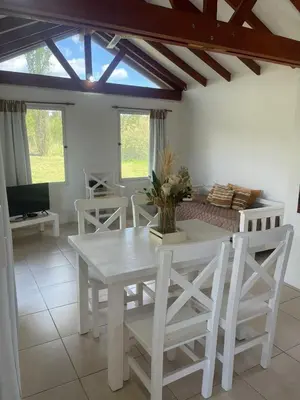 a dining room with a white table and chairs at Cabaña Aguaribay in Mina Clavero