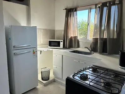a kitchen with a white refrigerator and a microwave at Cabaña Aguaribay in Mina Clavero