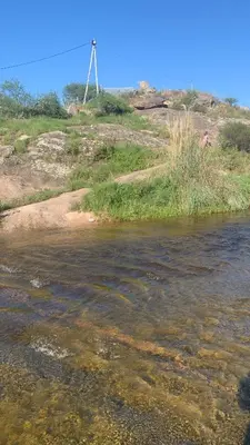 a stream of water with a windmill in the background at La Roca in Estancia Vieja