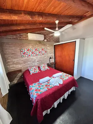 a bedroom with a large bed with red sheets and pillows at Cabaña Alamo in Mina Clavero