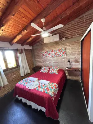 a bedroom with a red bed and a ceiling fan at Cabaña Alamo in Mina Clavero