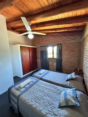 a bedroom with two beds and a ceiling fan at Cabaña Alamo in Mina Clavero