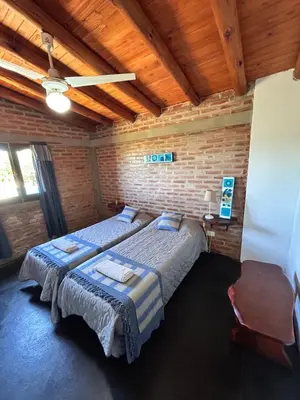 a bedroom with two beds and a brick wall at Cabaña Alamo in Mina Clavero