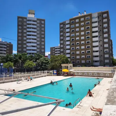a group of people in a swimming pool with tall buildings at Gama Villasol Temporario in Cordoba