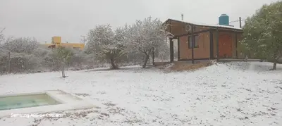 a house covered in snow in front of a building at Los Chivos in Villa Cura Brochero
