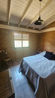 a bedroom with a large bed in a brick wall at Los Chivos in Villa Cura Brochero
