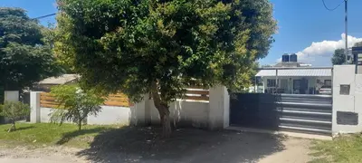 a tree in front of a house with a fence at Cabañas cochico in Villa Carlos Paz